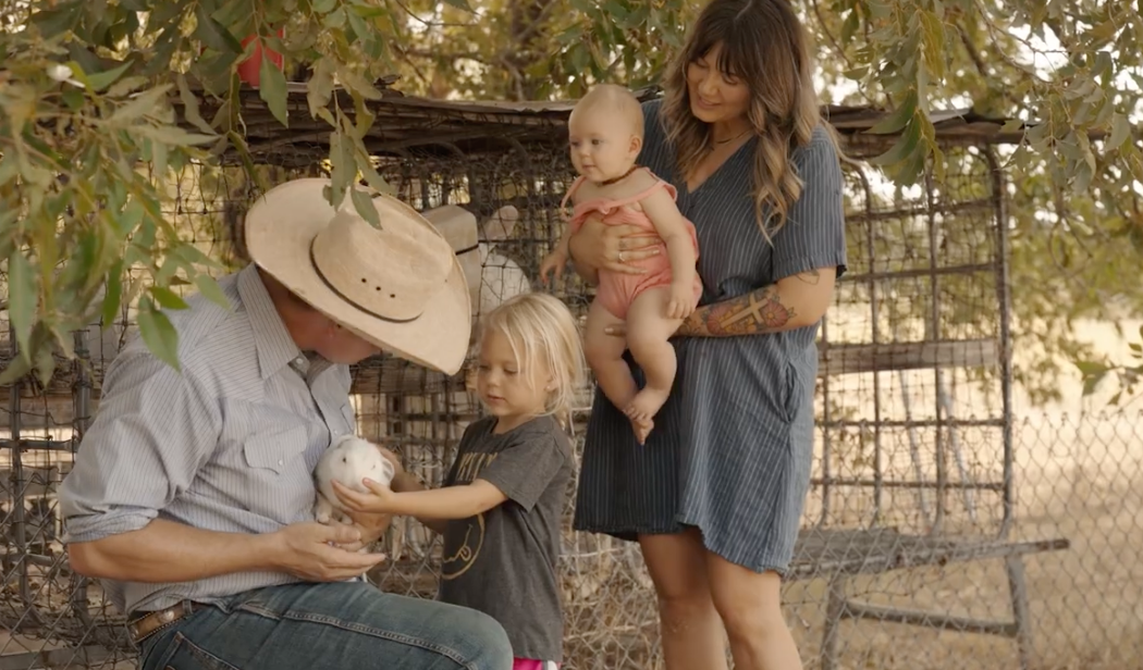 A ranch family introducing their children to a rabbit