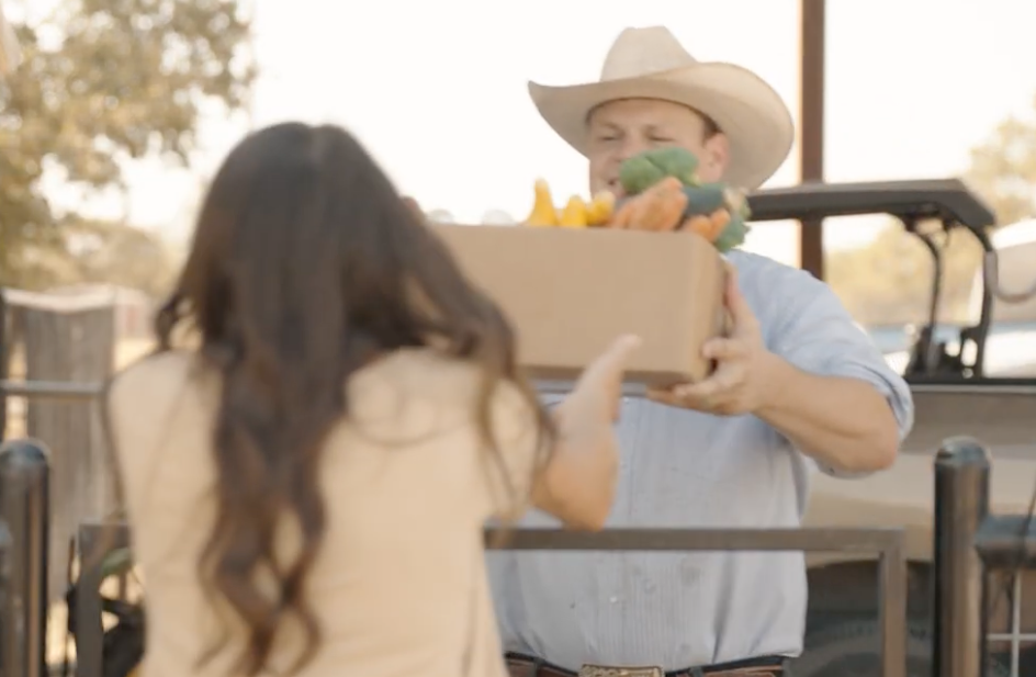 Handing off a box of fresh vegetables at pickup