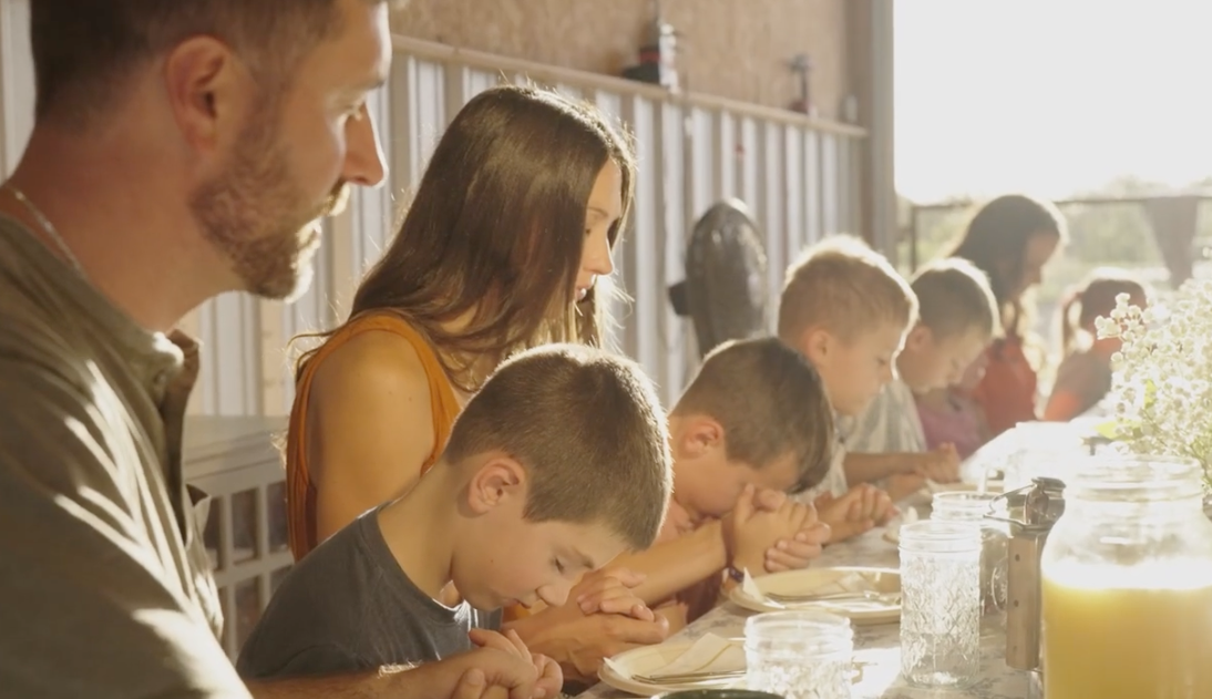 A family gathered around the table in prayer before a meal