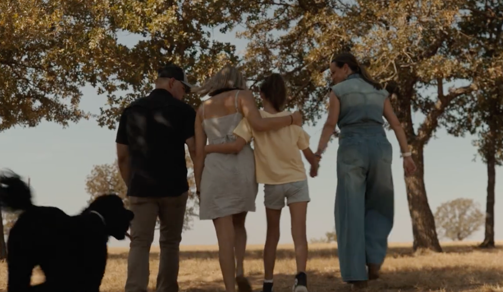 A family walking together under the trees on the ranch