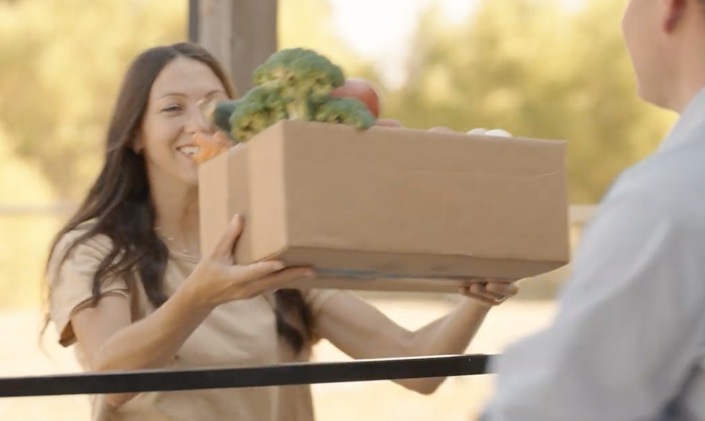 A resident receives a box of fresh produce from the Shared Farm